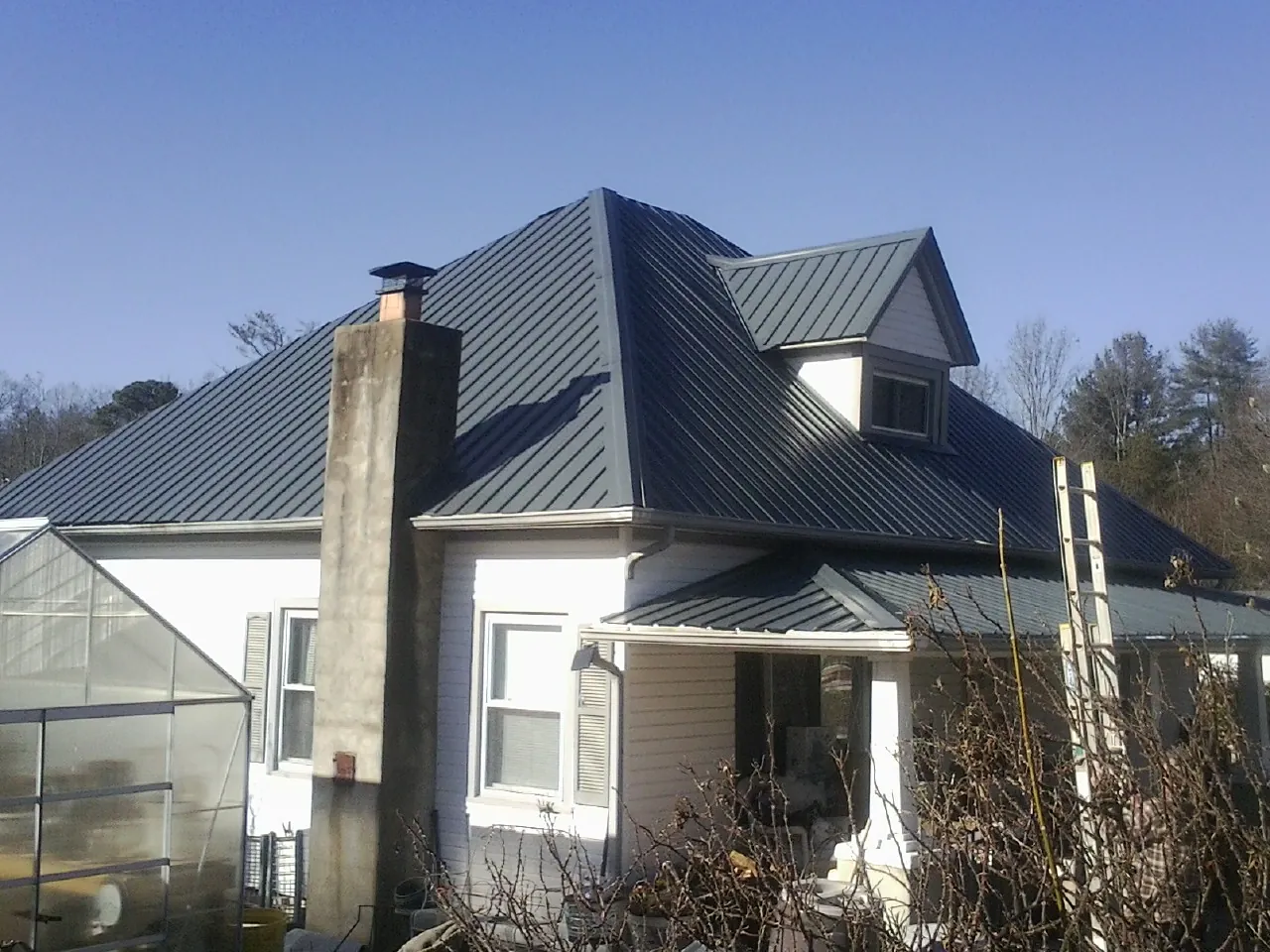 Dark blue standing seam metal roof on a white farmhouse with dormer — Slate & Tile Roof Repair by Roofing Brothers in Lewisport
