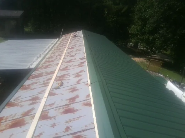 Old rusted panels beside newly installed green metal roofing — Wind Damage Roof Repair by Roofing Brothers in Lewisport