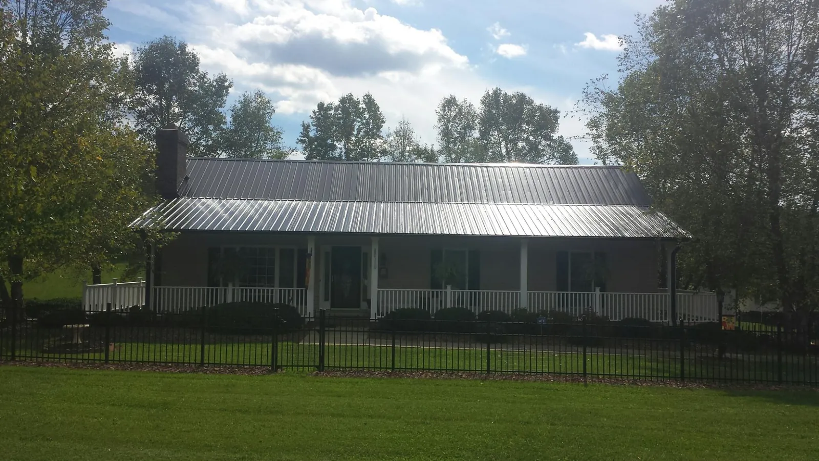 Gray metal roof on a brick ranch with a full width front porch — Gutter Guard Installation work by our crew in Lewisport