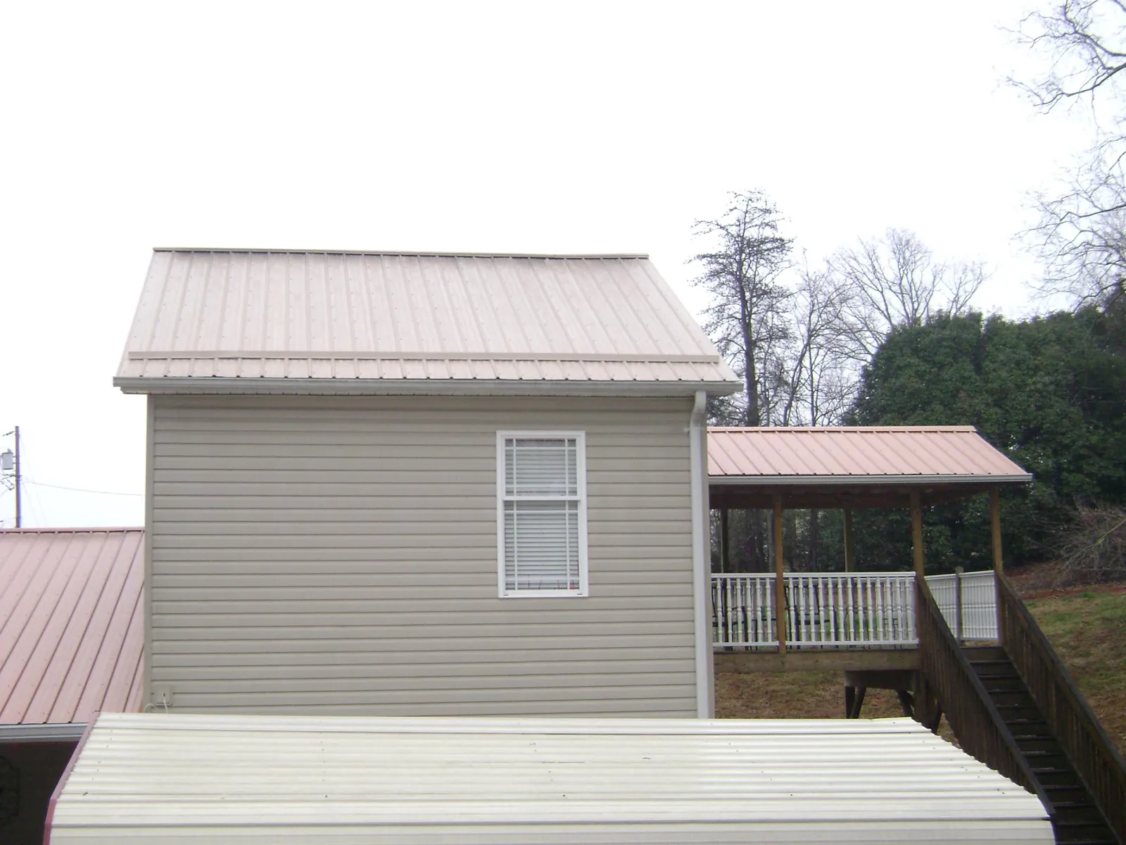 Tan metal roofs on a two story addition and attached porch, from a Roof Replacement job in Lewisport