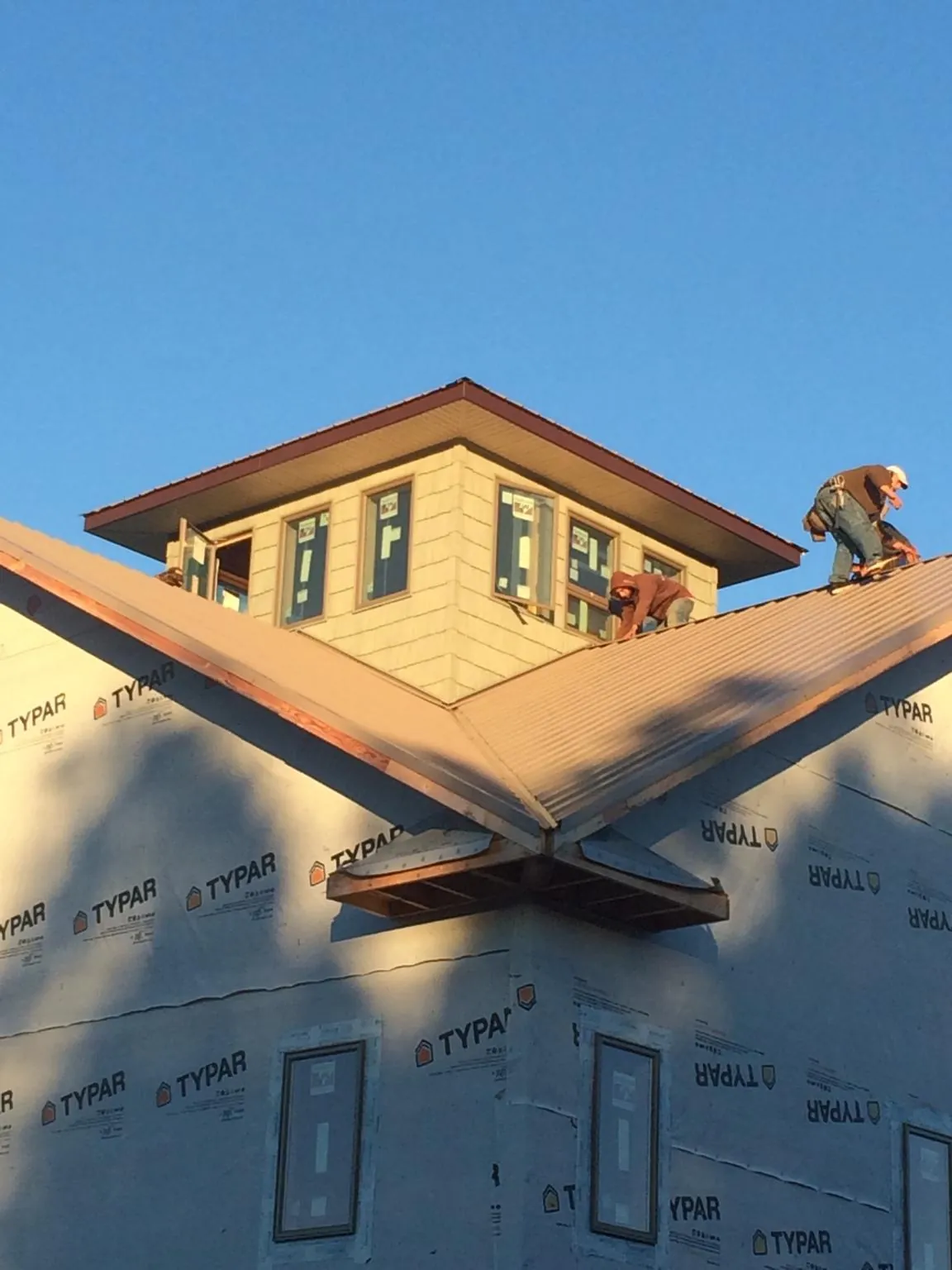 Roofers working around a rooftop cupola on a new metal roof at sunset — Roof Waterproofing in Lewisport by Roofing Brothers